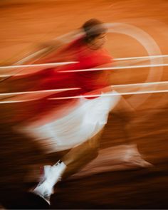 a blurry photo of a man running in the street with a red shirt and white skirt