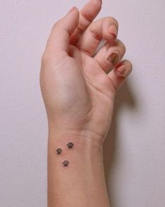 a person's hand with a small dog paw tattoo on their left wrist and the other arm