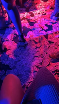 people are sitting on the floor covered in money notes and playing with cell phones at night