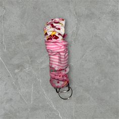 a pink and white striped umbrella laying on top of a gray floor next to a keychain