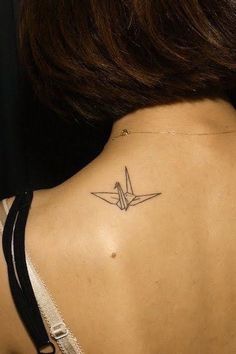 the back of a woman's neck with an origami bird tattoo on it