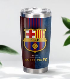 a can of barcelona fc on a table next to a plant with leaves in the background