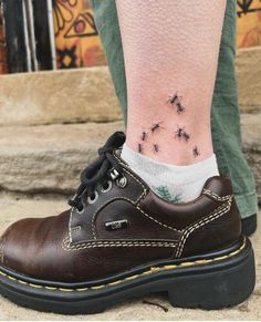 a person's foot with small black bees on the shoe and white socks behind them