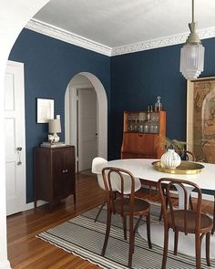 a dining room with blue walls and wooden flooring is featured in the instagram