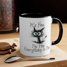 a black and white coffee mug sitting on top of a table next to a spoon