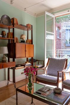 a living room filled with furniture next to a large glass window covered in bookshelves