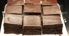 there are many pieces of chocolate cake on the trays that have been cut into squares