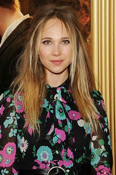 a woman standing in front of a movie poster wearing a black and pink floral dress