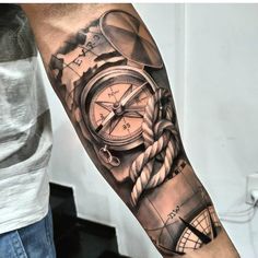 a man's arm with a compass and rope tattoo on it