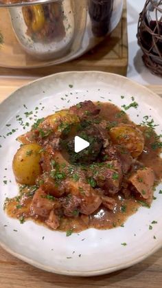 a white plate topped with meat and gravy on top of a wooden table