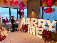 a man and woman standing in front of a sign that says marry me