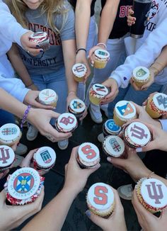 a group of people holding up cupcakes with numbers on them