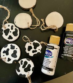 some crafting supplies are laying out on a black table with white and brown cow prints