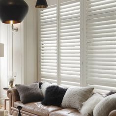 a living room filled with furniture and windows covered in white plantation shutters that are open to the outside