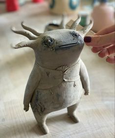 a person is touching the head of a clay animal