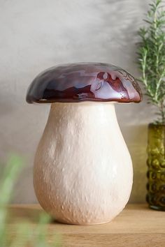 a mushroom shaped vase sitting on top of a wooden table