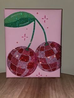 two cherries on a pink background with green leaves and sparkles in the center