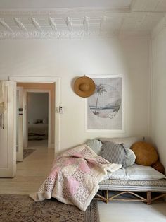 a bed sitting in a bedroom next to a white wall with paintings on the walls