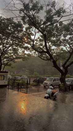 a motor scooter parked in the middle of a parking lot on a rainy day