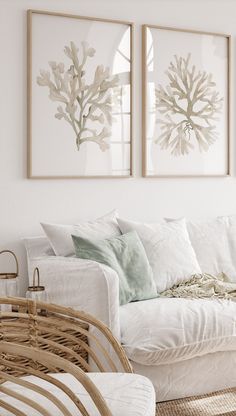 a living room with white couches and paintings on the wall above them, along with wicker chairs