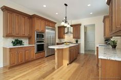 a large kitchen with wooden cabinets and stainless steel appliances in the center, along with marble counter tops