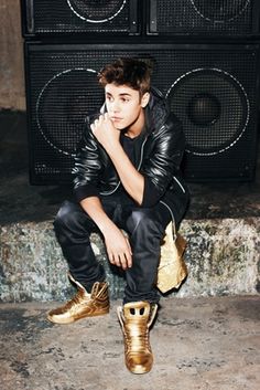 a young man sitting on top of a pair of gold shoes