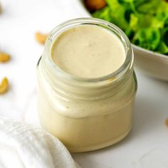 a small jar filled with dressing next to a salad