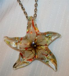 Lovely Sculpt Ambertone Flower Speckled Lampwork Star Starfish Pendant Necklace View My Other Items For Sale This lovely silvertone necklace features a mid-sized sculpted lampwork glass pendant with a wonderful sheen and shine.  It has colorful design with an ambertoned flower in the center.  It shines with goldtone speckles.  The reverse has a speckled finish and it measures 2 1/4 inches wide and 2 1/4 inches long.  The chain is 24 inches and closes with a safety catch.  It is in new condition. **************** Thank you for viewing my listings today!  I am always happy to answer any questions or offer additional help or information.  I offer combined shipping on multiple auction wins.  The shipping costs listed are for domestic shipping in the US.  Generally, the lowest flat rate interna Lampwork Glass Pendants, Starfish Pendant, Colorful Design, Fashion Jewelry Necklaces, Glass Pendant, Glass Pendants, Starfish, Fashion Watches, Jewelry Necklace Pendant