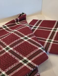 two pieces of red and green knitted blanket on the floor next to each other