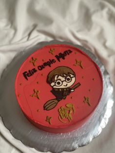 a red cake with an image of harry potter on it's side and gold lettering