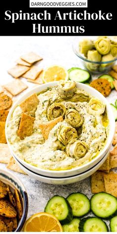 a bowl filled with dip surrounded by crackers and cucumbers