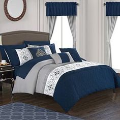 a bed room with a neatly made bed and blue comforter set on the floor