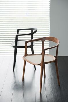 two chairs sitting next to each other on top of a hard wood floor in front of a window