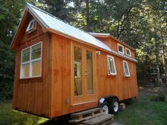 the tiny house is built on wheels and has a ramp leading up to it's front door