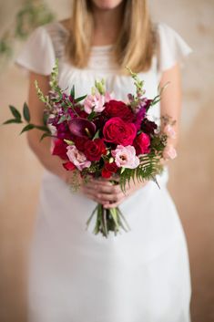 a woman holding a bouquet of red and pink flowers