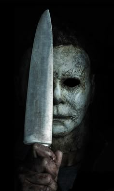 a man holding a large knife in his hand and wearing a creepy mask on the face