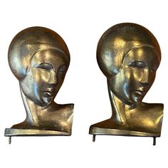 two metal head sculptures sitting next to each other