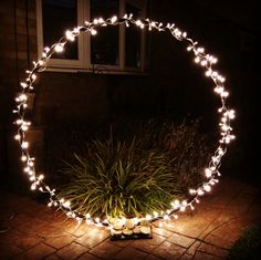 a circular light up mirror sitting on top of a brick floor next to a plant