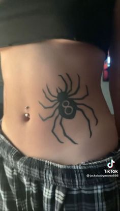 a woman's stomach with a spider tattoo on her belly and the bottom part of her abdomen