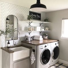 a washer and dryer in a room with white tiles on the walls, shelves above them