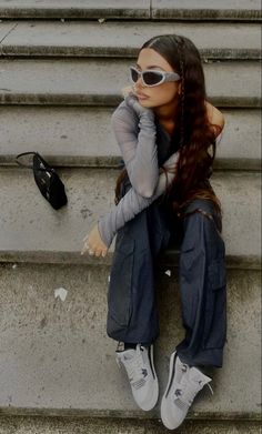 a young woman sitting on the steps with her head in her hands and wearing sunglasses