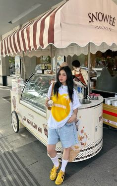 a woman standing in front of a food cart with an ice cream vendor behind her