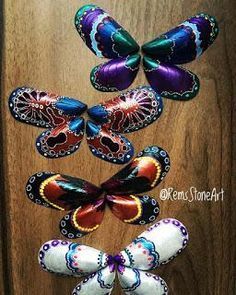 several colorful butterflies are arranged on a wooden surface, one is purple and the other is red