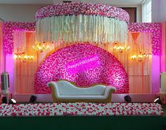 the stage is decorated with pink and white flowers, along with a couch for seating