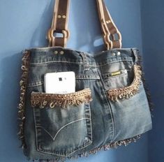 a cell phone is in the pocket of a jean purse hanging on a blue wall