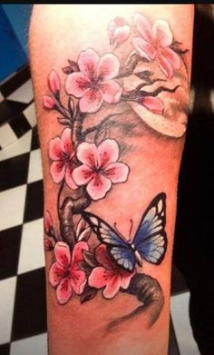 a woman's leg with pink flowers and a blue butterfly on the left thigh