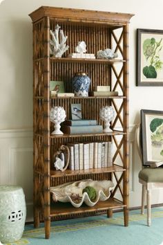 a wooden shelf with books and vases on it next to a chair in a living room