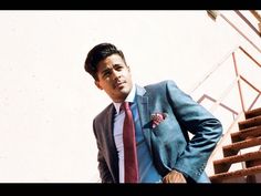 a man in a suit and tie standing next to stairs