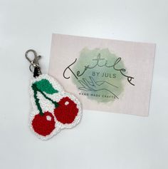 a crocheted keychain with two cherries on it and a business card