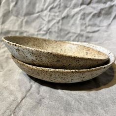 two bowls sitting on top of a white cloth covered table next to eachother